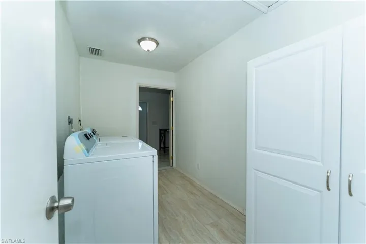 Laundry room with washing machine and dryer and light wood finished floors