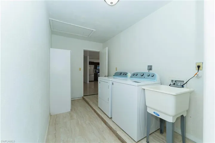 Laundry area with separate washer and dryer, light wood finished floors, and attic access
