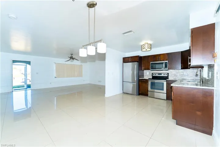 Kitchen with ceiling fan, appliances with stainless steel finishes, pendant lighting, dark brown cabinets, and backsplash