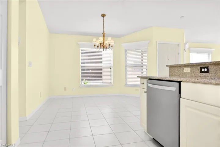 Kitchen with hanging light fixtures, plenty of natural light, stainless steel dishwasher, and an inviting chandelier