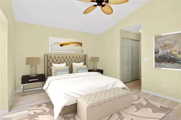 Primary bedroom with ceiling fan, plank tile flooring, and vaulted ceiling