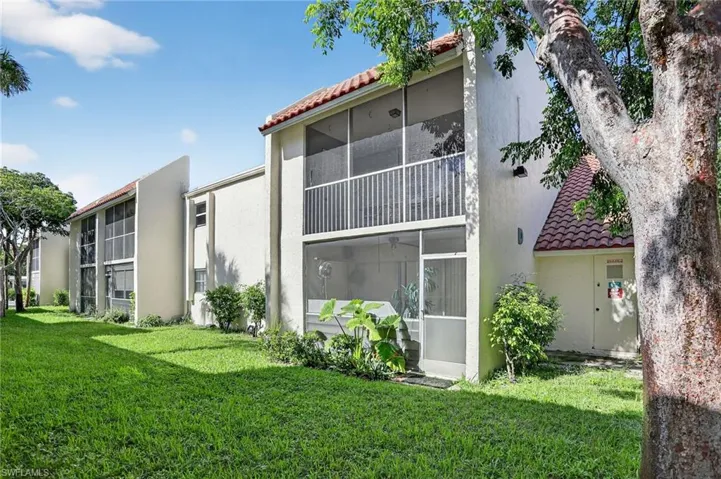 Back of property with a sunroom, a yard, and a tile roof