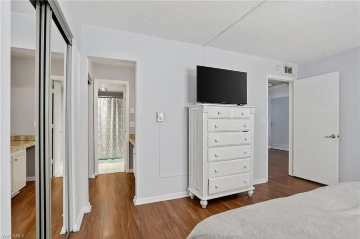 Bedroom with a closet, dark wood-style flooring, a textured ceiling, and ensuite bath