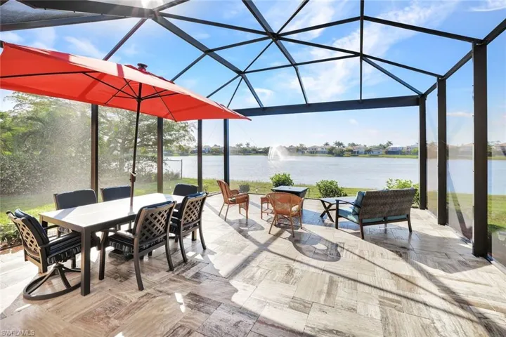 View of patio featuring a water view and glass enclosure