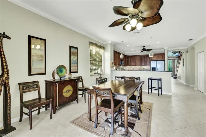 Tiled dining space featuring crown molding and ceiling fan