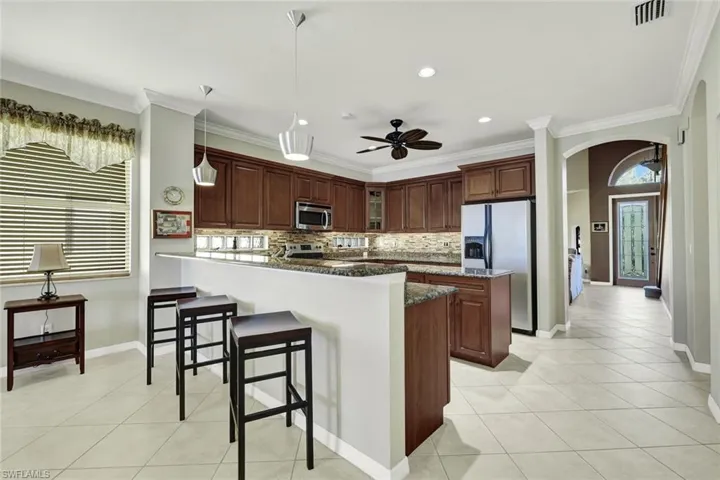 Kitchen featuring appliances with stainless steel finishes, ornamental molding, tasteful backsplash, and a kitchen island