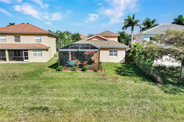 Rear view of house with a yard, a sunroom, and a lanai