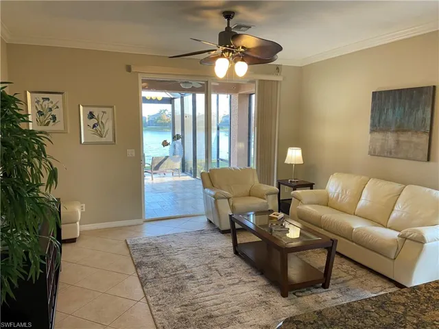 Living room featuring ceiling fan, a water view, light tile patterned floors, and ornamental molding