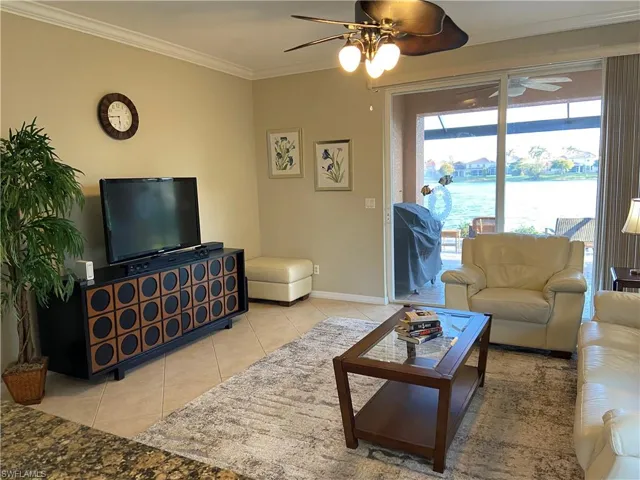 Tiled living room featuring ceiling fan and crown molding