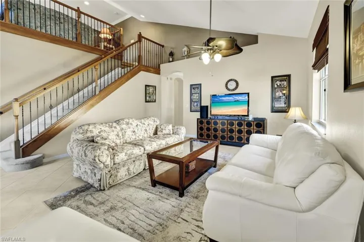 Tiled living room featuring high vaulted ceiling and ceiling fan