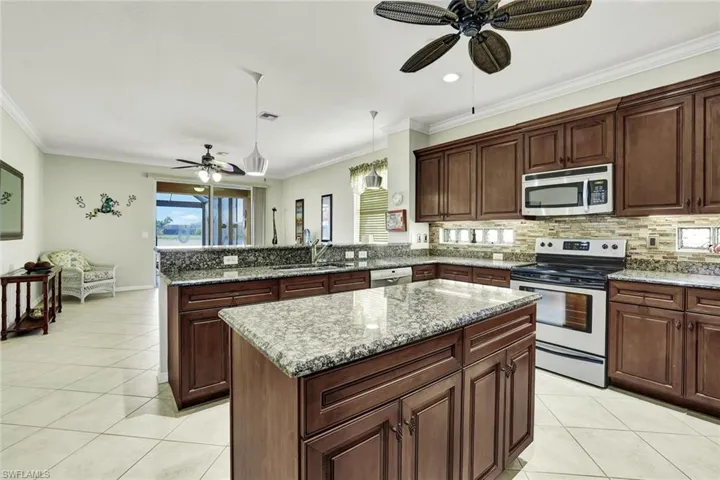 Kitchen featuring ornamental molding, stainless steel appliances, sink, decorative light fixtures, and a center island