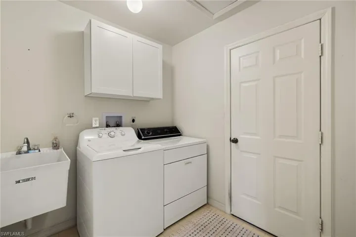 Laundry area with cabinets, washer and clothes dryer, sink, and light tile patterned floors