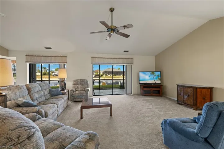 Carpeted living room featuring lofted ceiling and ceiling fan