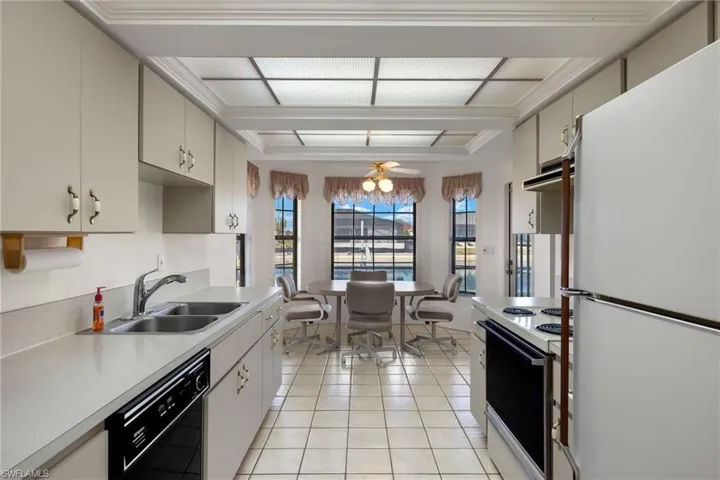 Kitchen with black dishwasher, sink, white fridge, light tile patterned floors, and electric stove