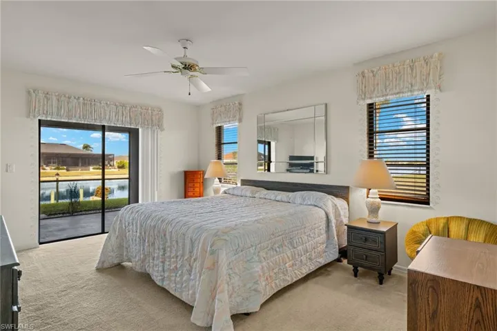 Carpeted bedroom featuring a water view, access to exterior, and ceiling fan