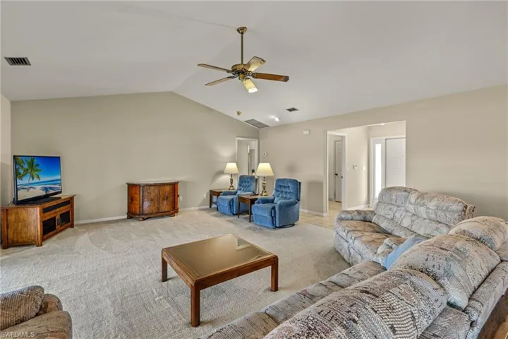 Living room with lofted ceiling, light carpet, and ceiling fan