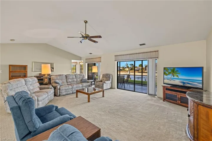 Carpeted living room featuring lofted ceiling and ceiling fan