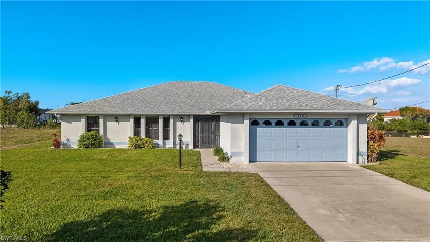 Single story home with a garage and a front lawn