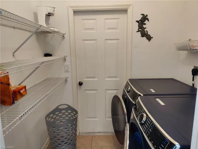 Washroom with washing machine and dryer and light tile flooring