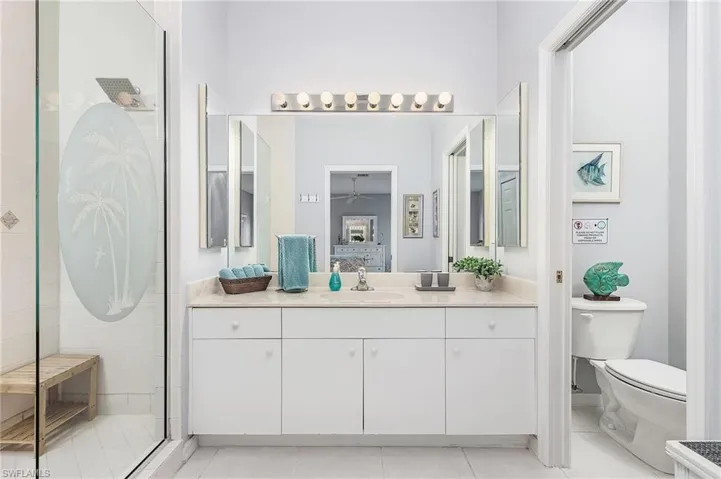 Bathroom featuring tile floors, a shower with shower door, vanity, and toilet