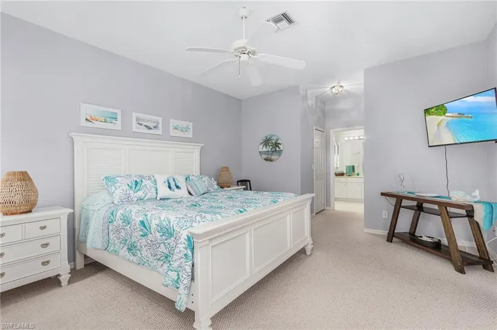 Bedroom featuring ceiling fan, connected bathroom, and light carpet