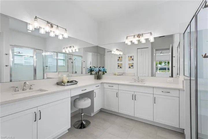 Bathroom featuring a shower stall, two vanities, and light tile patterned flooring