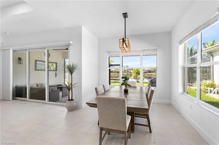 Dining space with light tile patterned floors, healthy amount of natural light, a water view, and a chandelier