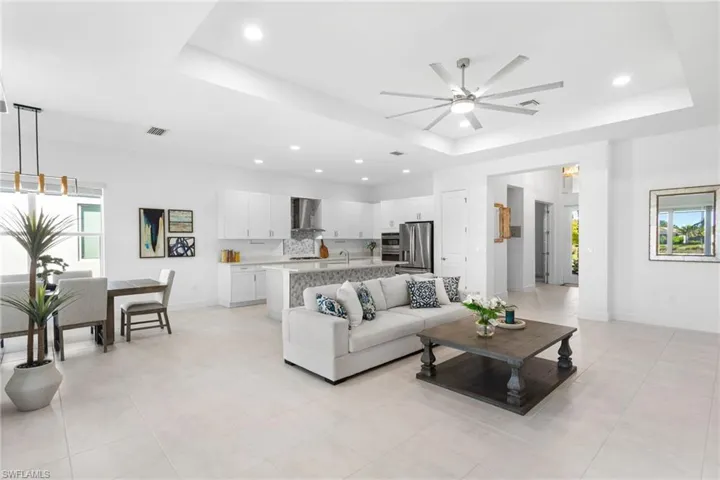 Living room featuring a raised ceiling, plenty of natural light, recessed lighting, and a ceiling fan