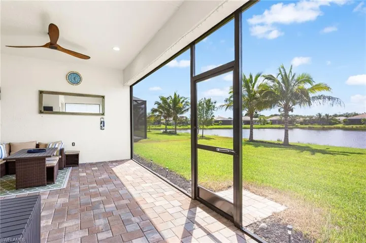 Unfurnished sunroom featuring ceiling fan, a water view, and a patio