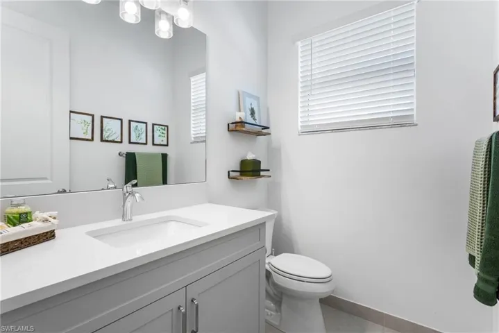 Half bathroom featuring vanity, healthy amount of natural light, and tile patterned floors