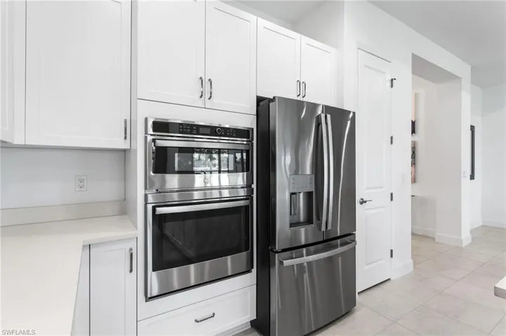 Kitchen featuring stainless steel appliances, white cabinets, and light tile patterned flooring