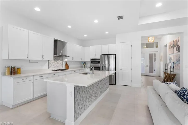 Kitchen featuring french doors, decorative backsplash, white cabinetry, stainless steel appliances, and recessed lighting