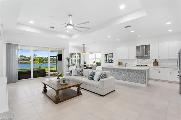 Living area featuring a tray ceiling, light tile patterned floors, recessed lighting, and a ceiling fan