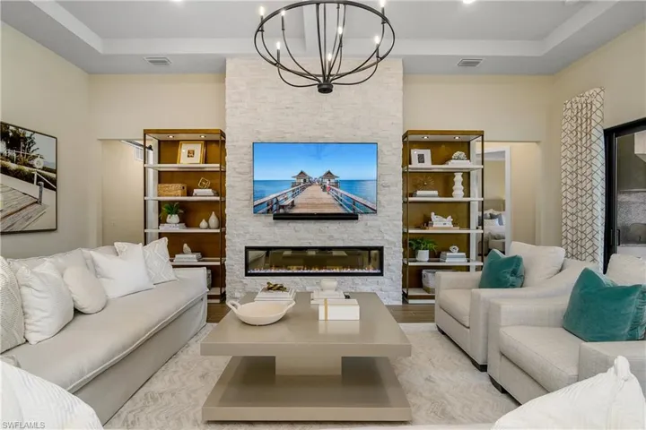 Large, open great room with stunning stone feature wall with built-in fireplace, designer lighting and tray ceilings.