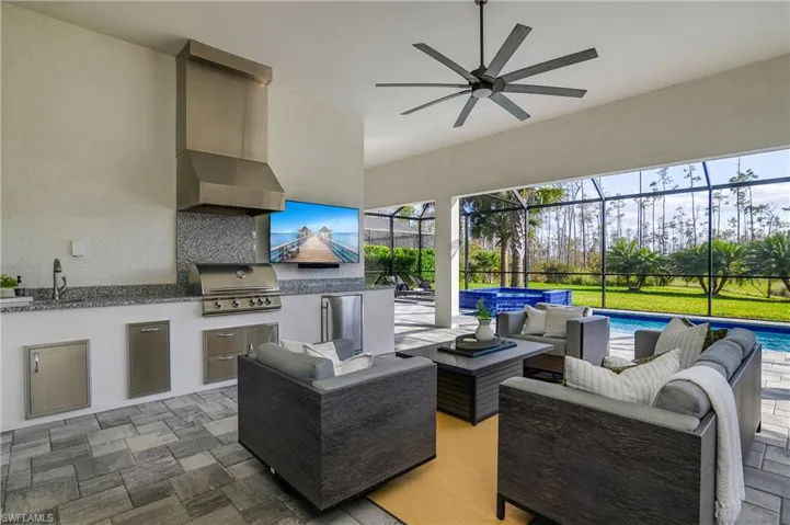 Outdoor kitchen includes oversized grill with overhead exhaust, beverage cooler, pull out trash can, sink, and additional storage space.