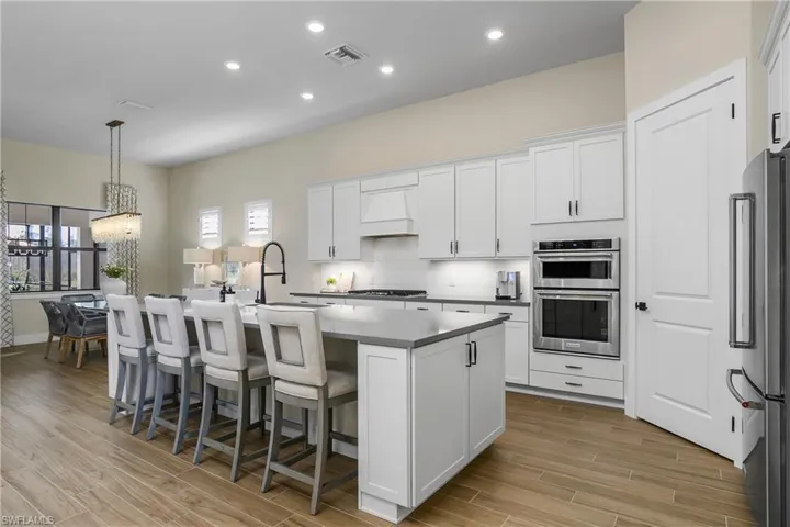 Kitchen is a chef's dream with natural gas stove, walk-in pantry, oversized island with side cabinet storage, stainless steel Kitchen Aid appliances, quartz countertops and timeless beveled subway tile backsplash.