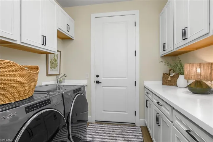Spacious laundry room with plenty of additional storage and counter space, a utility sink, and a custom barn door entry.