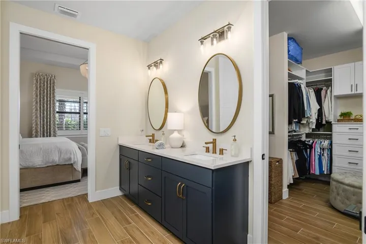 Owner bath with upgraded fixtures, custom mirrors and lighting, dual sinks, and huge walk-in closet with custom built in shelving.