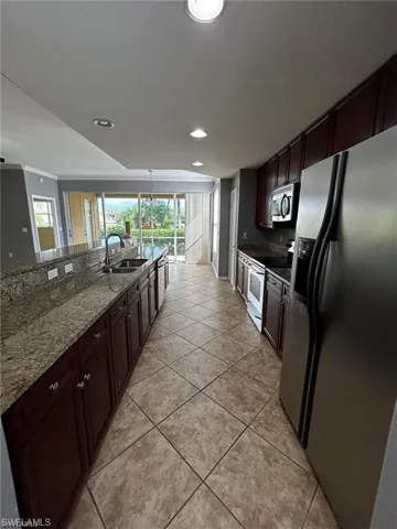 Kitchen with stainless steel appliances, a sink, plenty of natural light, light tile patterned floors, and recessed lighting