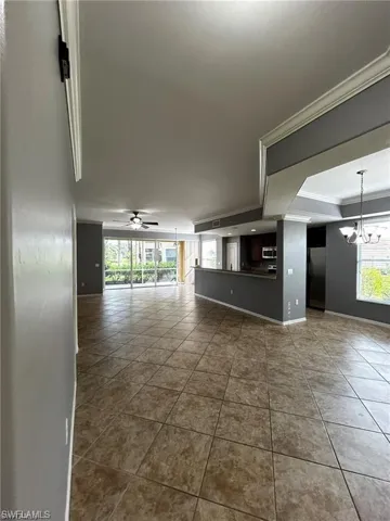Spare room featuring a chandelier, crown molding, dark tile patterned flooring, a ceiling fan, and baseboards