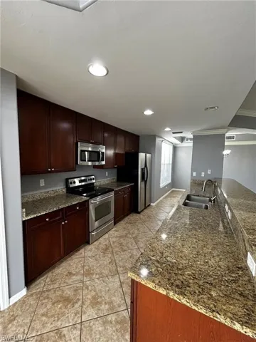Kitchen with stainless steel appliances, a sink, light tile patterned floors, baseboards, and recessed lighting