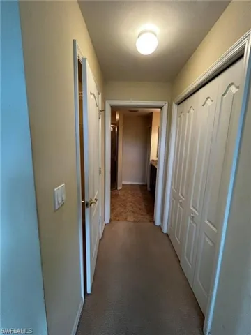 Hall featuring carpet flooring and baseboards
