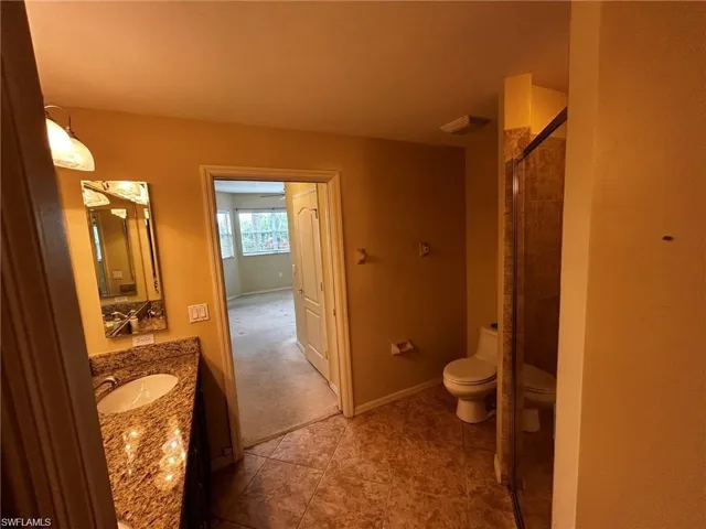 Bathroom with toilet, vanity, a stall shower, and baseboards