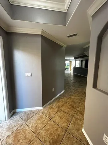 Hall with crown molding, tile patterned flooring, and baseboards