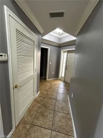 Corridor featuring ornamental molding, tile patterned floors, and baseboards