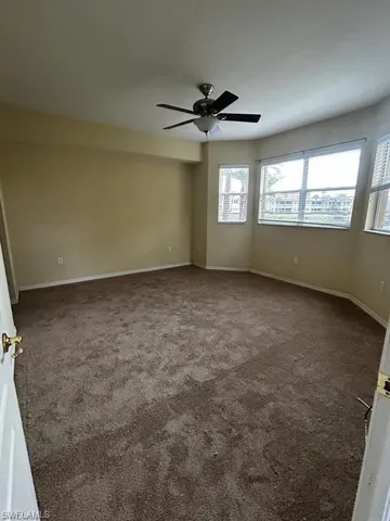 Empty room featuring carpet floors, ceiling fan, and baseboards