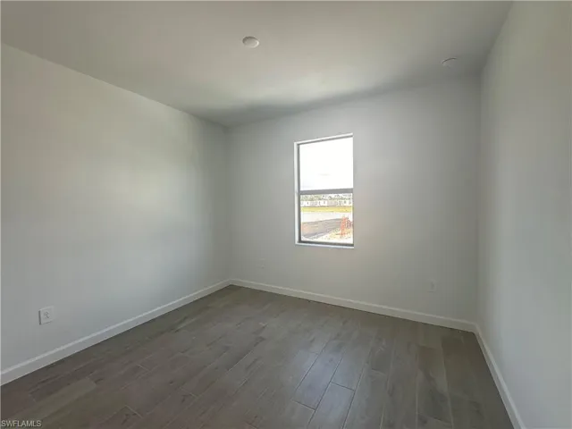 Empty room with dark hardwood / wood-style flooring