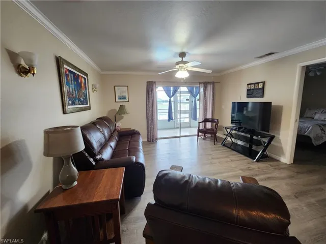 Living area featuring light wood-style flooring, a ceiling fan, and ornamental molding