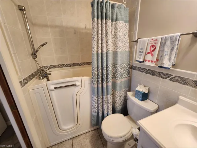 Full bath with tile walls, vanity, and shower / tub combo