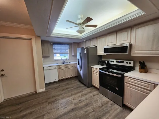 Kitchen featuring crown molding, stainless steel appliances, light countertops, light wood finish cabinetry, and a ceiling fan